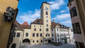 ein großes Gebäude mit einem Uhrturm darauf in der Unterkunft Hotel Platin in Regensburg