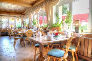 a restaurant with wooden tables and chairs and windows at Hotel am Liepnitzsee in Wandlitz