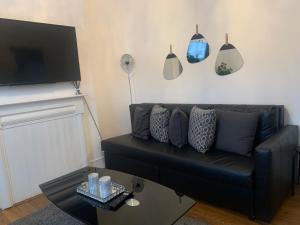 a living room with a black couch and a tv at L A PLACE Croydon, London in Norwood