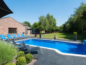 a swimming pool with blue chairs next to a house at The Old Mill, 7 storey,, dog friendly outdoor pool & bbq in Stoke Ferry