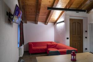 a living room with a red couch and a table at Lo Stambecco Bianco Chalet in Aosta