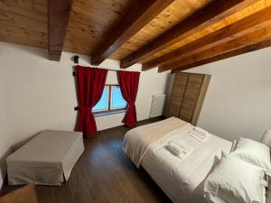 a bedroom with a bed and a window with red curtains at Lo Stambecco Bianco Chalet in Aosta