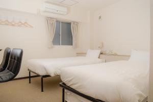 two beds in a white room with a window at HOTEL G-CUE 大阪谷町 in Osaka
