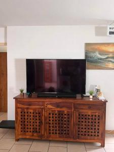 a flat screen tv on top of a wooden entertainment center at Agréable Villa équipée avec piscine et barbecue in Sainte-Suzanne