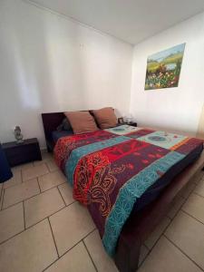 Un dormitorio con una cama con una manta de colores. en Agréable Villa équipée avec piscine et barbecue, en Sainte-Suzanne
