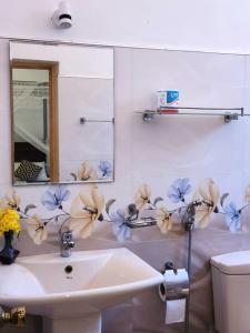 a bathroom with a sink and flowers on the wall at Sun sea guest home in Tangalle