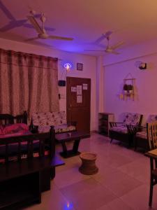 - un salon avec éclairage violet, canapés et chaises dans l'établissement Raga Homestay 2BHK- A homely guesthouse experience, à Guwahati