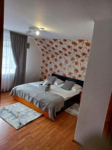 1 dormitorio con 1 cama con pared de flores en VILA SIMONA, en Moieciu de Sus