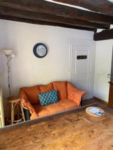 an orange couch in a living room with a clock on the wall at Gîte des Moriers Blois Bord de Loire in Blois