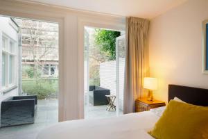 een slaapkamer met een bed en een glazen schuifdeur bij NEW 4p renovated apartment @BEST location Jordaan in Amsterdam