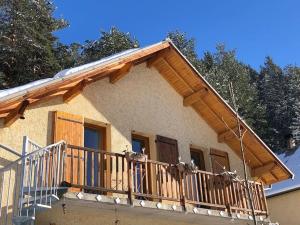 ein Haus mit einem Balkon mit einem Holzgeländer in der Unterkunft La Boissette d’en O in Montgenèvre