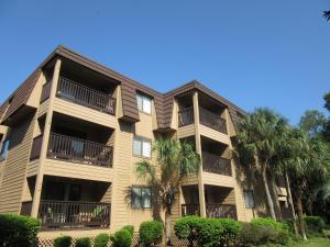 un grand immeuble d'appartements avec des palmiers devant dans l'établissement Hilton Head Island Beach and Tennis Resort, à Île de Hilton-Head