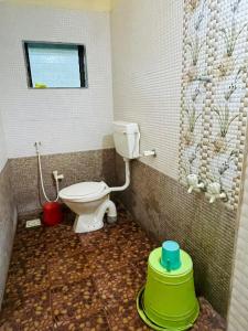 a bathroom with a toilet and a tiled wall at Krupasagar Homestay in Malvan