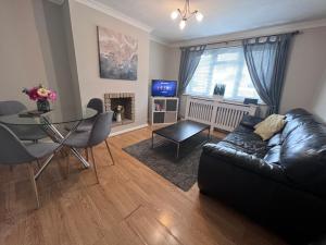 a living room with a black leather couch and a table at Croydon apartment with parking in London
