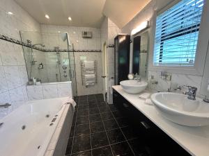 La salle de bains est pourvue de 2 lavabos, d'une baignoire et d'une douche. dans l'établissement Fontainebleau Luxury B&B, à Hanmer Springs