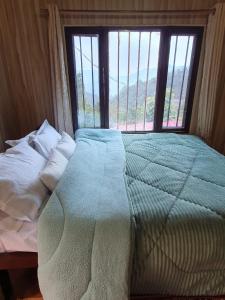 a bed in a room with a large window at Aum 108 Retreat - Rishikesh Mountains in Rishīkesh