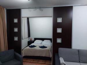 a bedroom with a mirror and a bed and a couch at Belváros közeli kertkapcsolatos lakás 1-től 5 főig in Debrecen