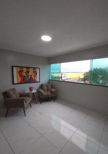 a living room with two chairs and two windows at Pousada Chapada do Araripe in Araripina