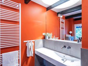 an orange bathroom with a sink and a mirror at Hyggeby - Architektenhaus mit Schleiblick, Sauna, etc in Ulsnis +28 photos