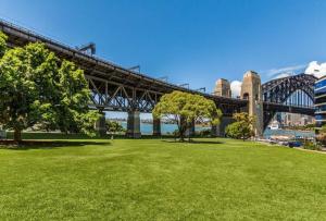 un pont sur un parc avec de l'herbe verte et des bâtiments dans l'établissement Opera & Harbour bridge view penthouse (3 rooms), à Sydney