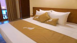 een groot bed met witte lakens en kussens erop bij Diyathra Escape in Galle