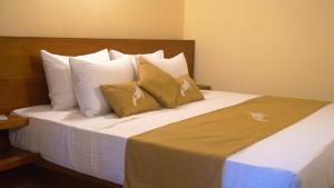 Cama en habitación de hotel con almohadas blancas en Diyathra Escape, en Galle