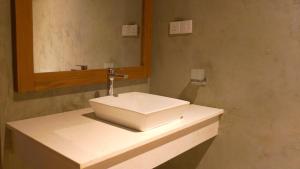een badkamer met een witte wastafel en een spiegel bij Diyathra Escape in Galle