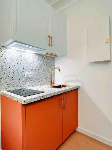 a kitchen with an orange sink and white cabinets at Studio Romantique Paris Moulin Rouge Montmartre in Paris