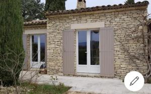 ein Steinhaus mit einer weißen Tür und Fenstern in der Unterkunft Maison provençale en pierres sèches in Gordes