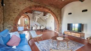 ein Wohnzimmer mit einem blauen Sofa und einem TV in der Unterkunft Colombaio di Montebenichi in Bucine