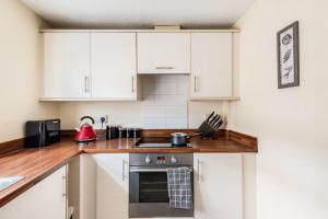 a kitchen with white cabinets and a red appliance at Lovely Town Centre 1 Bed Nr Country & River Walks 