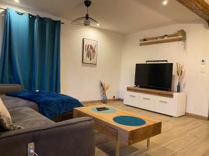 ein Wohnzimmer mit einem Sofa und einem Flachbild-TV in der Unterkunft Douce évasion in Beinheim