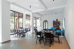 a dining room with black chairs and tables and windows at The Secret Cove by Stay ALYF, Baga in Baga