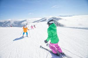 grupa osób jeżdżących na nartach po pokrytym śniegiem stoku w obiekcie Sunshine @ Rosie Design Chalet w mieście Bad Kleinkirchheim