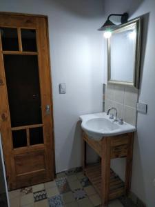 a bathroom with a sink and a mirror and a door at La Casita in Neuquén