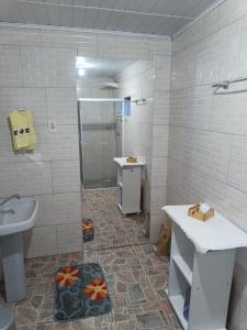 uma casa de banho branca com um lavatório e um chuveiro em Casa Amarela em Lages