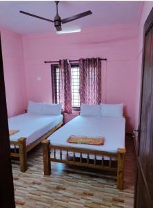 2 Betten in einem Zimmer mit rosa Wänden in der Unterkunft Quality Inn Varkala in Varkala
