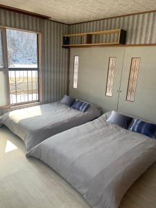 two beds in a room with two windows at Sound Garden Biei, Forest in Shibinai