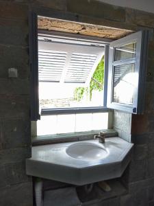 a sink under a window in a bathroom at To Spitaki House in Perdika