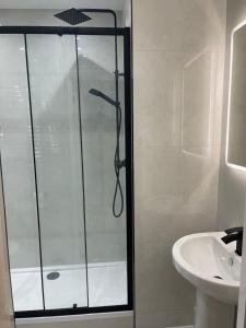 a shower with a glass door next to a sink at Ground Floor 2 Bed Holiday Flat in Eastbourne