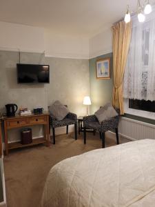 a bedroom with two chairs and a television on the wall at Amberlea Guest House in Swanage
