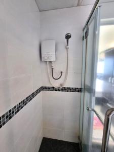a shower in a white tiled bathroom at Green Ocean Seaview Apartment in Batu Ferringhi