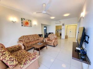 a living room with couches and a flat screen tv at Green Ocean Seaview Apartment in Batu Ferringhi