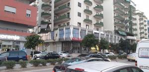 un gran edificio con coches estacionados frente a él en Comfort Hotel, en Fier