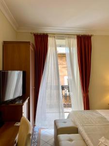 a bedroom with a bed and a tv and a window at Hotel Akropolis - Museum Hotel in Taranto