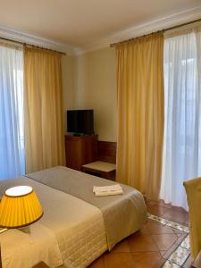 una camera con letto, TV e tende di Hotel Akropolis - Museum Hotel a Taranto