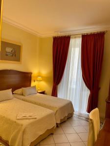 塔兰托Hotel Akropolis - Museum Hotel的一间卧室设有两张床,窗户配有红色窗帘
