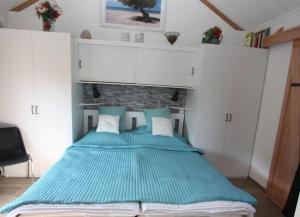 a bedroom with a large bed with blue sheets at Bungalowpark Mooyeveld in Egmond-Binnen