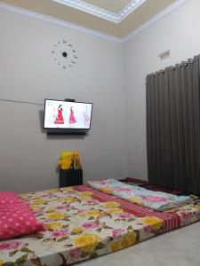 Un dormitorio con una cama y un televisor en la pared. en Almahyra Homestay Syariah, en Bukittinggi