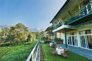 a house with tables and chairs on a balcony at Lamrin Norwood Green Palampur, Himachal Pradesh in Pālampur